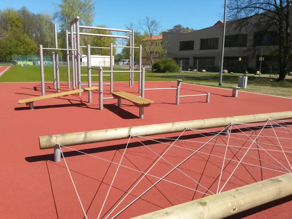 Ein Spiel- und Sportplatz an der Europaschule in Falkensee. Zu sehen ist ein Klettergerüst auf einem roten Boden.